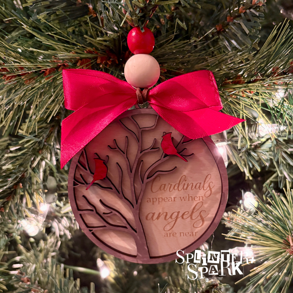 Decorative Christmas ornament with pink bow and engraved design on a tree.