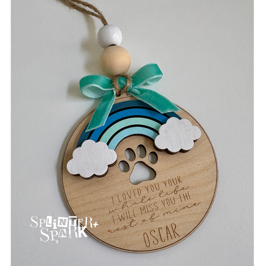 Wooden ornament with rainbow, paw print, and text on a gray background