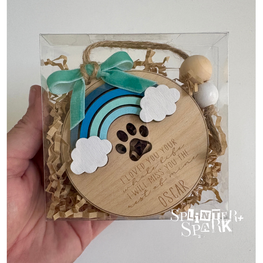 Hand holding a wooden plaque with paw print and rainbow design, branded 'Splendid Spark'.